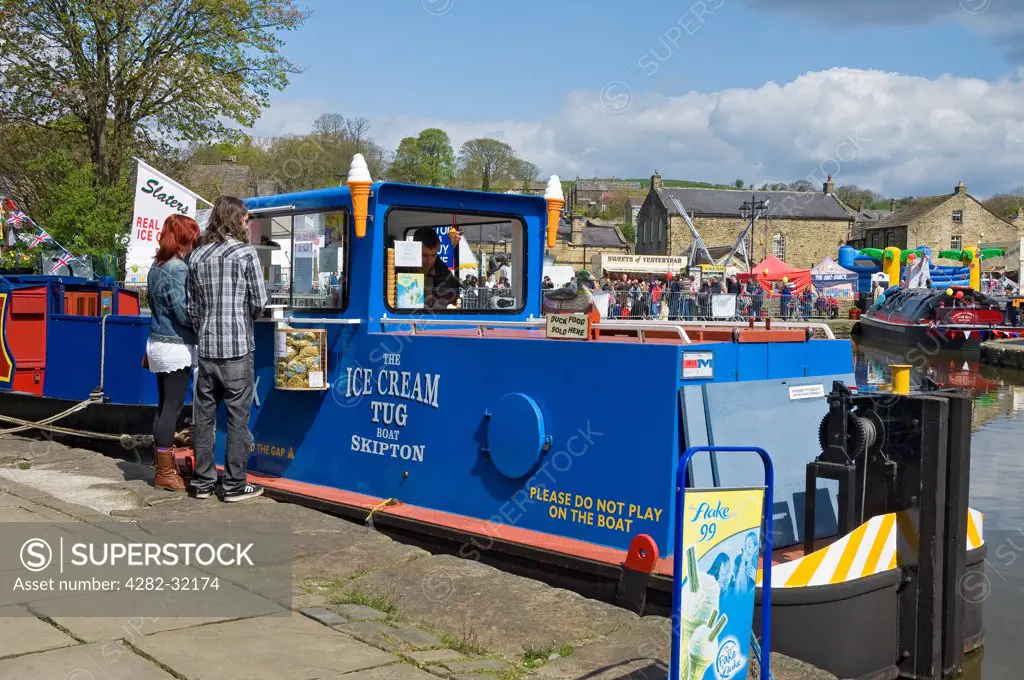 England, North Yorkshire, Skipton. Couple buying ice cream at The Ice Cream tug boat.