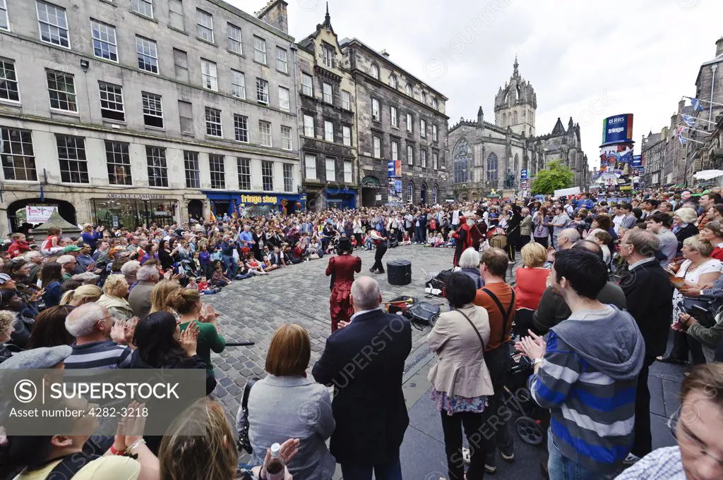Scotland, City of Edinburgh, Edinburgh. A street performer entertains a large crowd in the high street during the Fringe at the Edinburgh Festival.