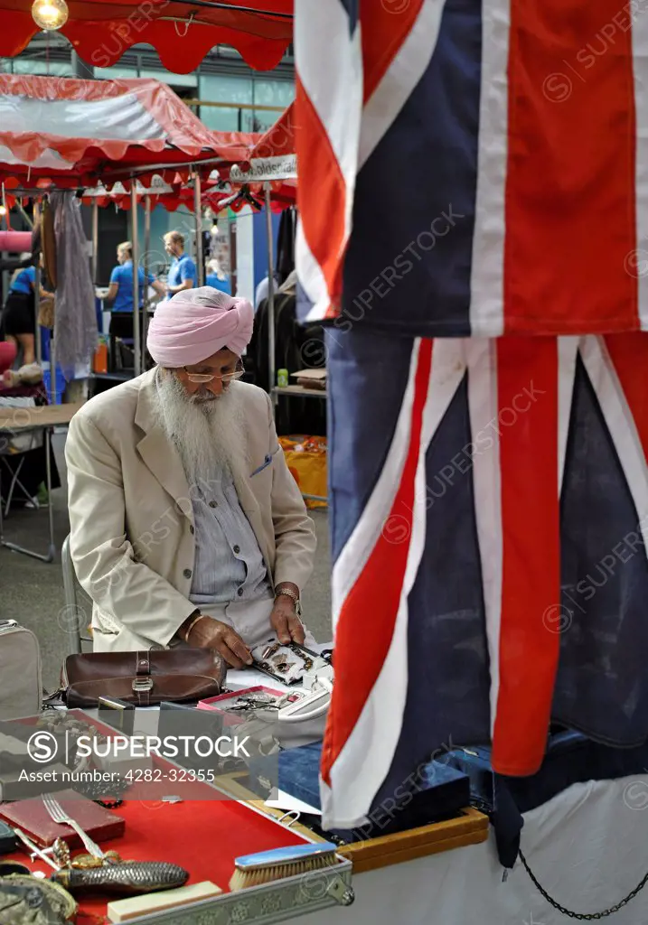 England, London, Spitalfields. A dedicated craftman working on his jewellery at Spitalfields Market in London.