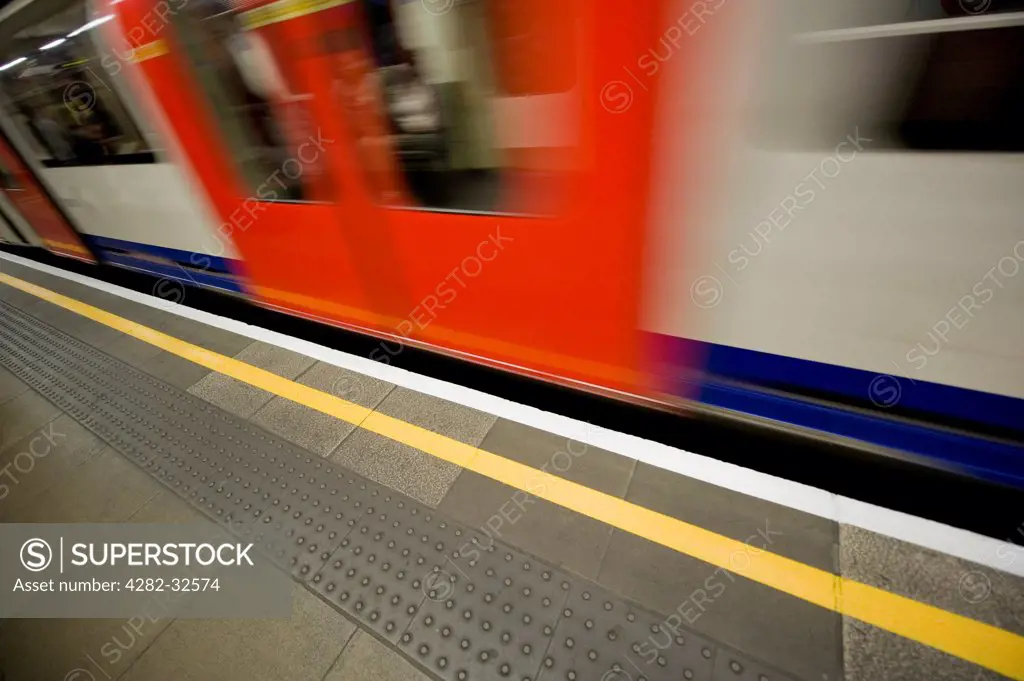 England, Greater London, London. A tube rushes past a platform on the London Underground system.