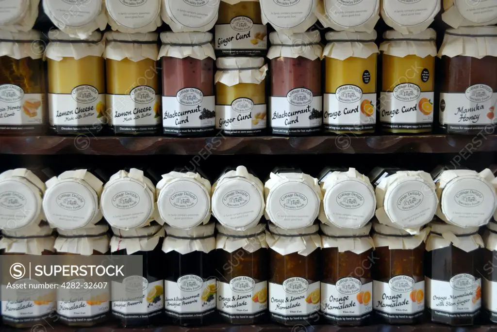 England, London, Muswell Hill. Jars of traditional curd and marmalade on display in a shop window.
