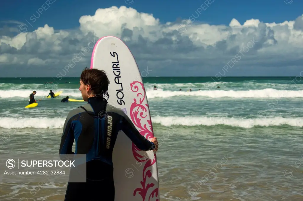 England, Cornwall, Newquay. Surfer holding his board at Newquay.