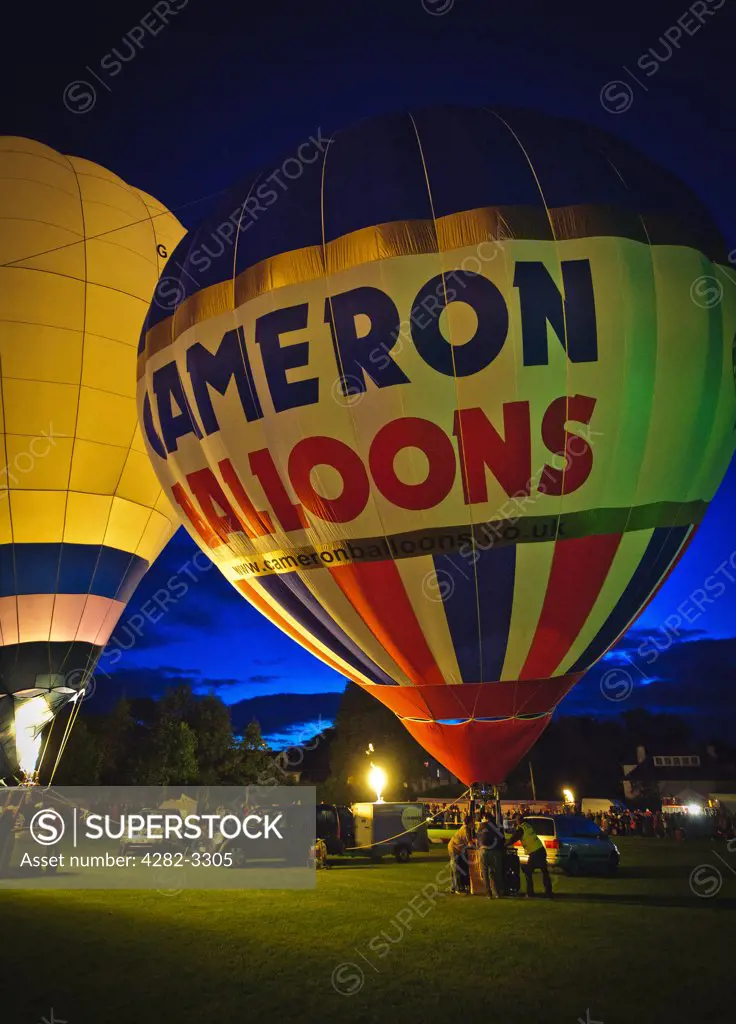 Scotland, South Lanarkshire, Strathaven. Balloonists inflating their hot air balloons at 'Evening Glow', a spectacular Saturday night extravaganza during the Strathaven Balloon Festival.