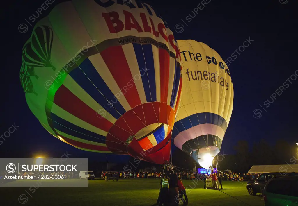 Scotland, South Lanarkshire, Strathaven. Balloonists inflating their hot air balloons at 'Evening Glow', a spectacular Saturday night extravaganza during the Strathaven Balloon Festival.