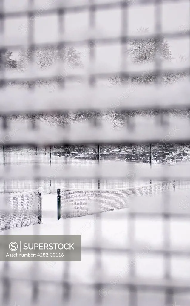 England, London, Camden. Looking through a snow-covered mesh fence at a snowed down tennis court in Waterlow Park in North London.