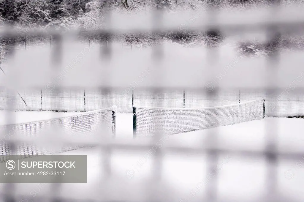 England, London, Camden. Looking through a snow-covered mesh fence at a snowed down tennis court in Waterlow Park in North London.