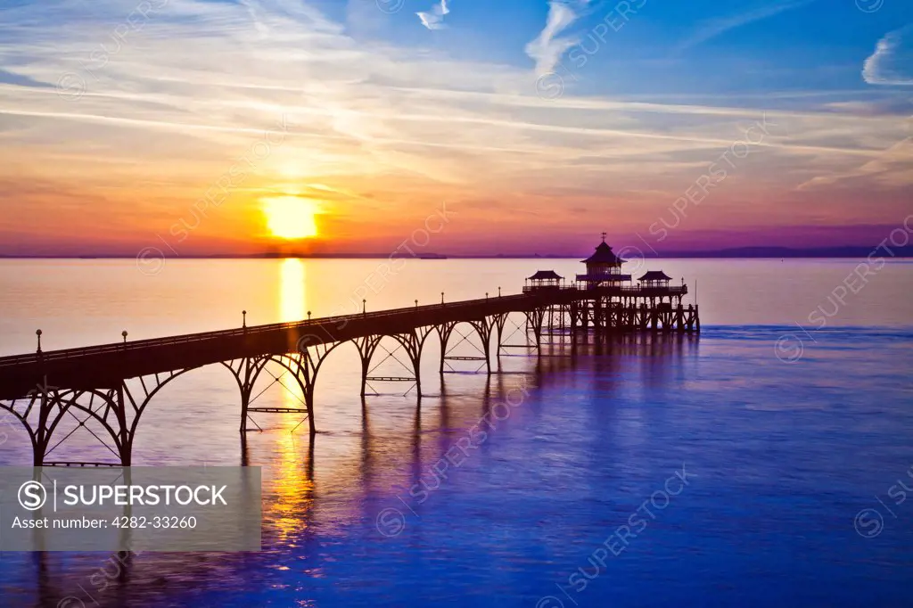 England, Somerset, Clevedon. The sun sets over the Bristol Channel behind the pier at Clevedon in Somerset.