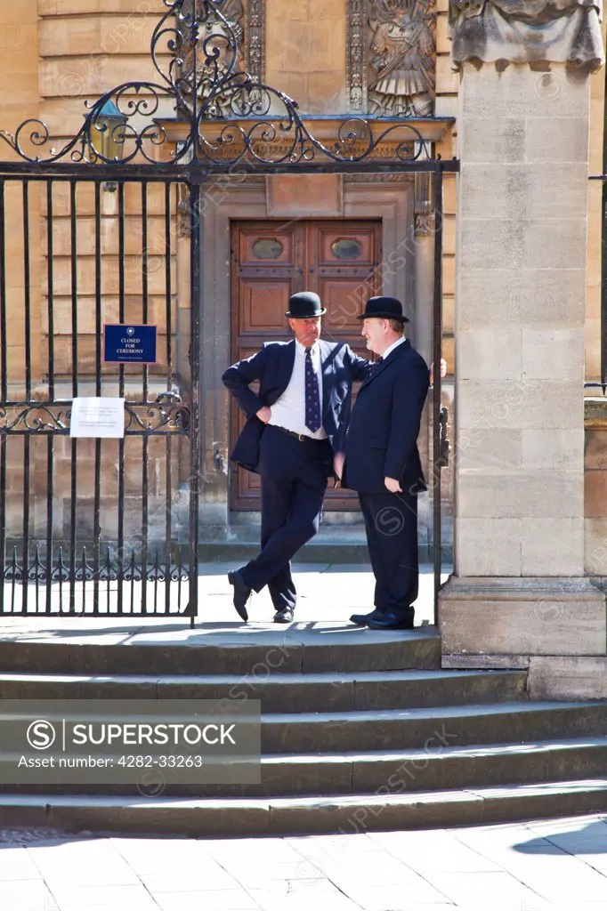 England, Oxfordshire, Oxford. Two Oxford bulldogs in traditional bowler hats outside the Sheldonian Theatre at Oxford University.