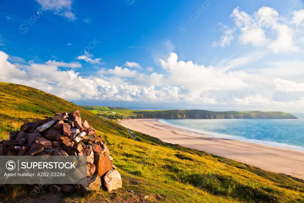 England, Devon, Woolacombe. Evening light falls on the cairn on top of Potters Hill overlooking Putsborough Sands and Baggy Point.