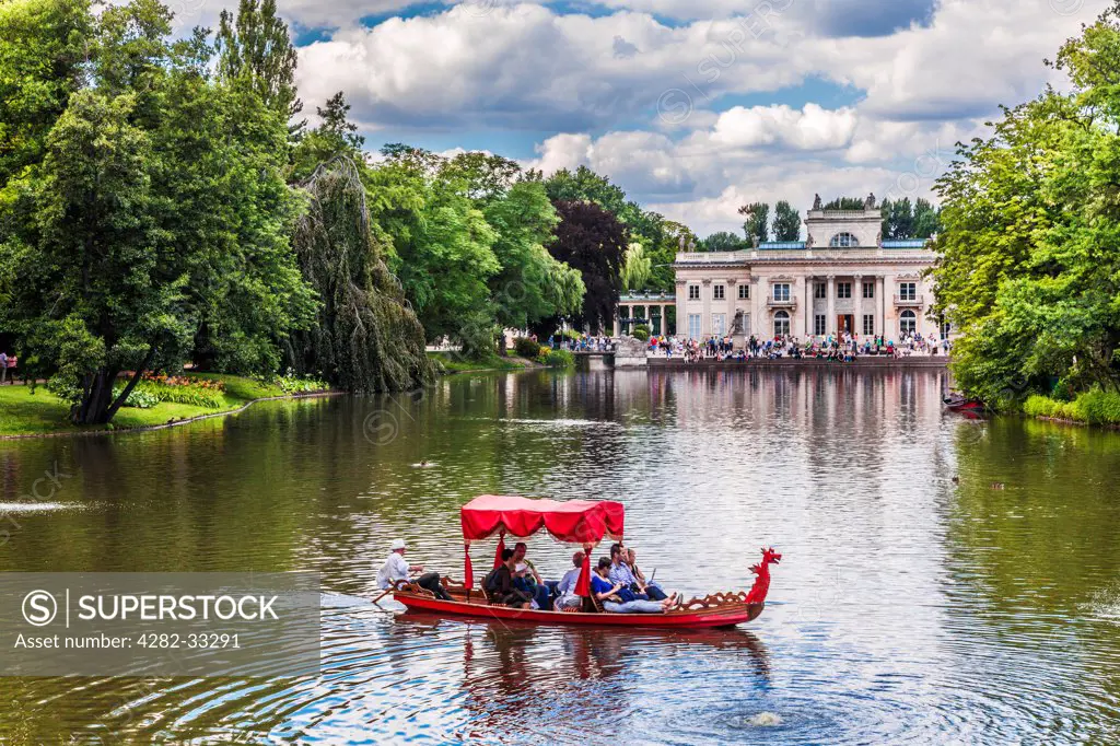 Poland, Mazovia Province, Warsaw. Tourists enjoy a gondola trip on the lake in Lazienki Park in Warsaw with the Palace in the background.