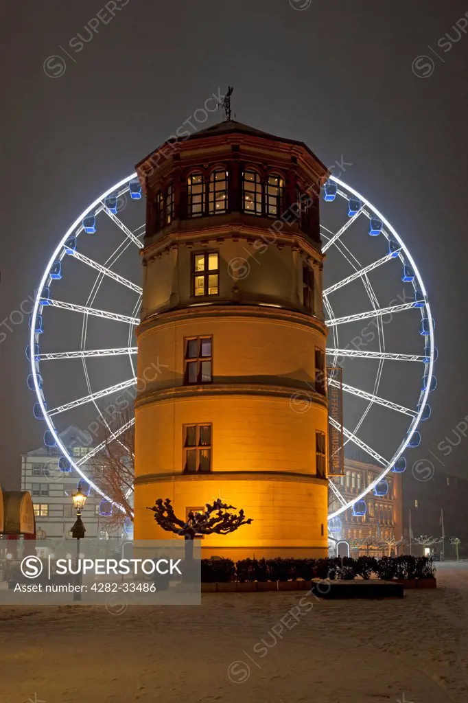 Germany, North Rhine Westphalia, Duesseldorf. An illuminated ferris wheel behind the Shipping Museum tower in Dusseldorf.