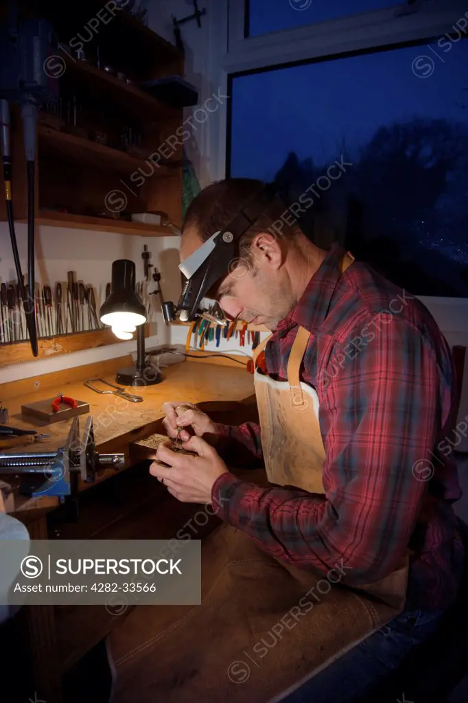 Wales, Monmouthshire, Monmouth. Man making jewellery at a workshop bench.