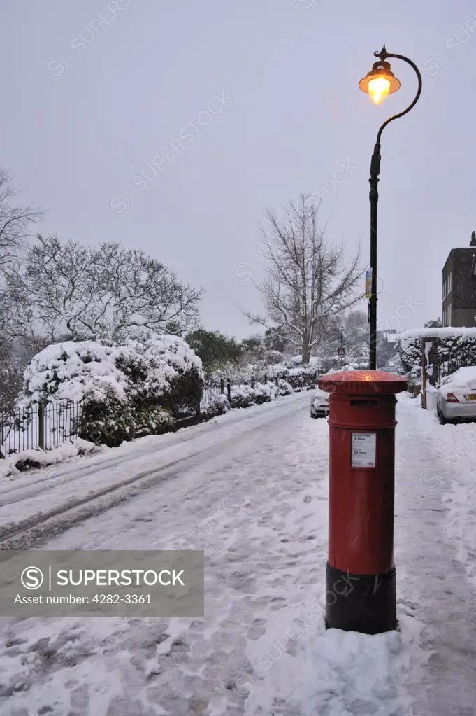 England, London, London. A London post box and street light surrounded by snow.