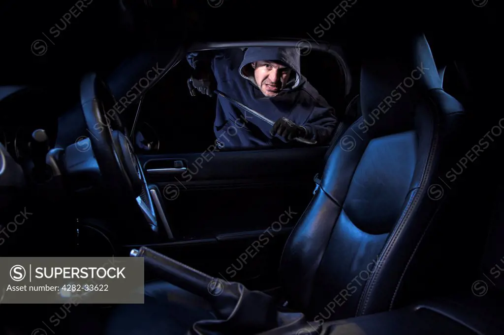 Wales, Monmouthshire, Monmouth. A man breaking into a parked car at night.