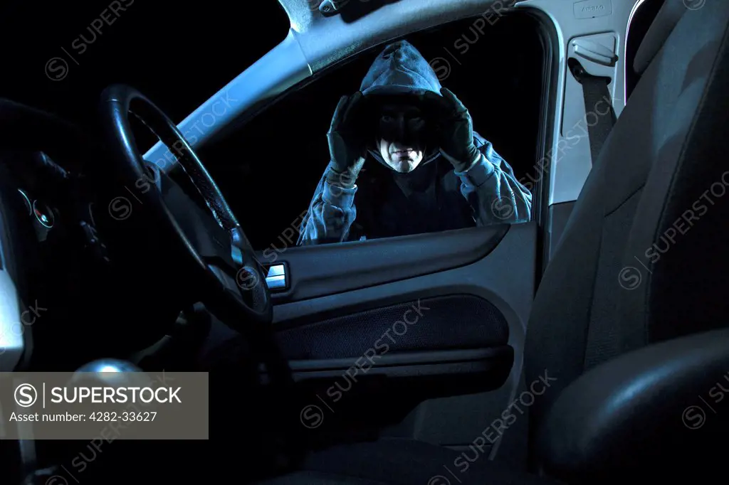 Wales, Monmouthshire, Monmouth. A man looking into a parked car at night.