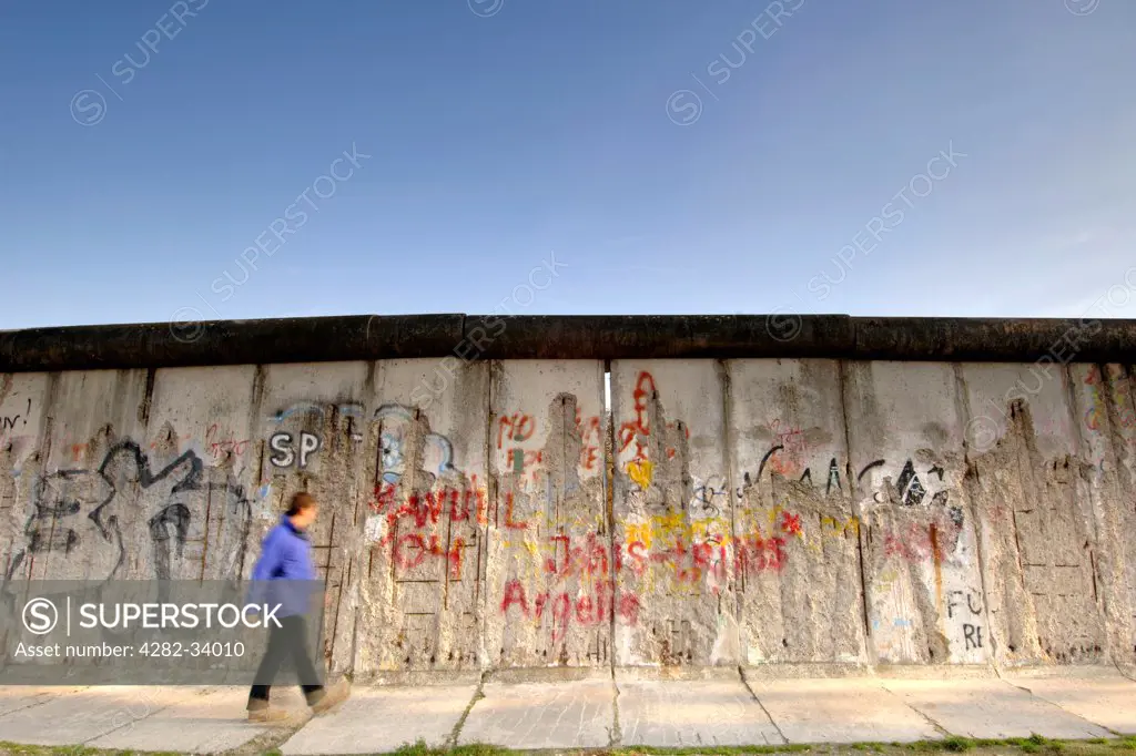 Germany, Berlin, East Side Gallery. A man walks past the Berlin Wall along Bernauer Strasse in East Berlin.