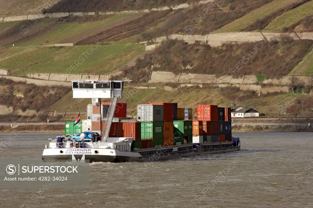 Germany, Hessen, Trechtingshausen. A container ship trawls along the Rhine river in Hessen Province.
