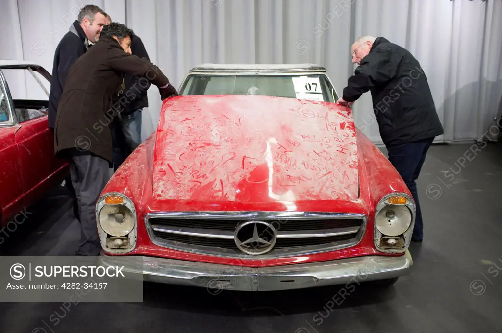 England, Surrey, Brooklands. Men inspecting an old Mercedes at a Historics auction for Brooklands in Mercedes World.