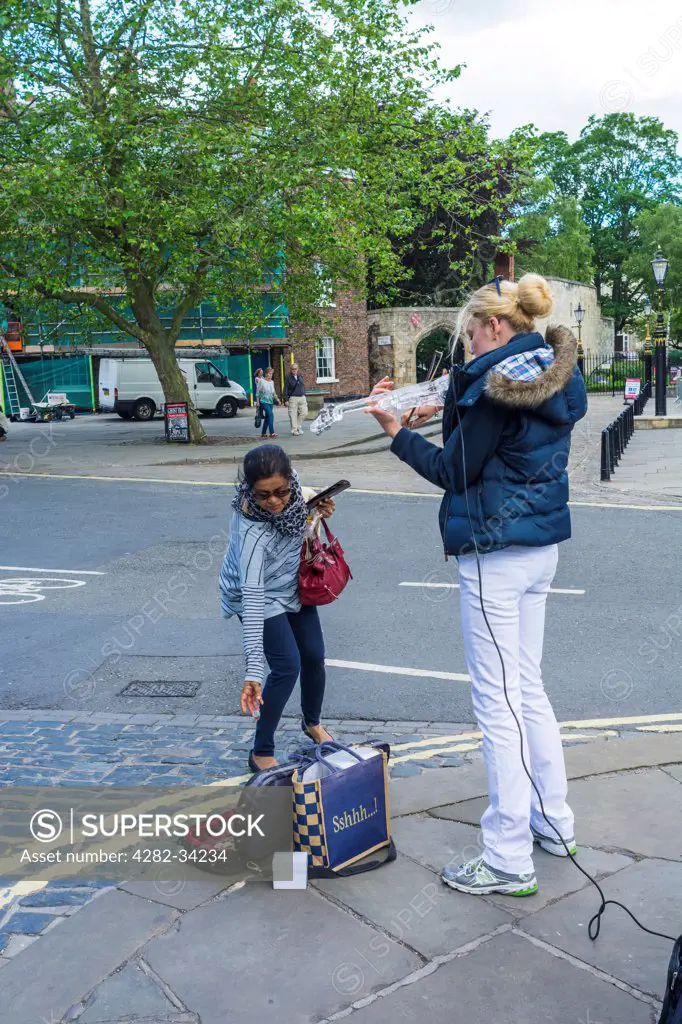 England, North Yorkshire, York. A tourist making a donation to a busker.