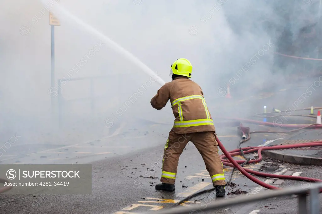 England, Essex, Basildon. A member of the Essex Fire Service tackles a fire with a hose.