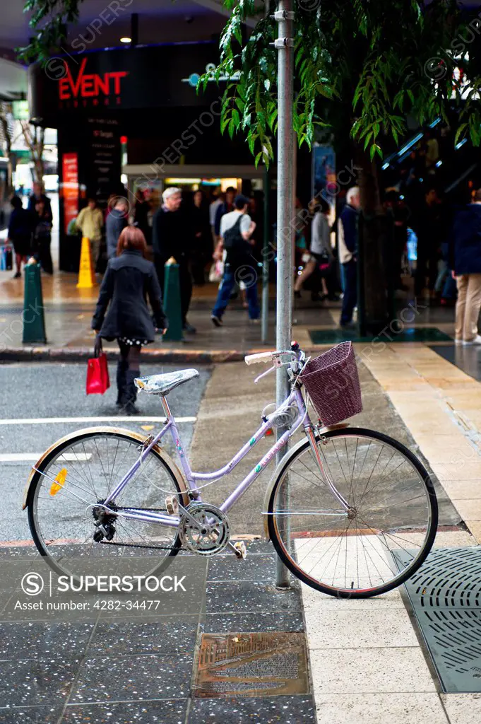 Australia, Queensland, Brisbane. A ghost bicycle leaning against a post on a street in Brisbane.