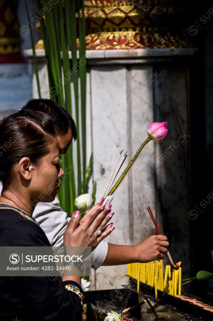 Thailand, Northern Thailand, Wat Phra That Doi Suthep. A woman worshipping at a shrine at Wat Phra That Doi Suthep in Chiang Mai in Thailand.