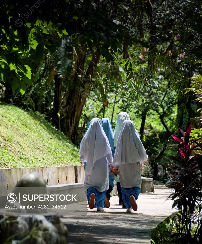 Malaysia, Federal Territory of Kuala Lumpu, Kuala Lumpur. A group of female Muslim students walking along a path.
