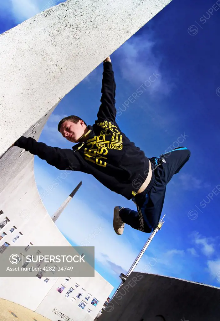 Wales, Clwyd, Rhyl. A parkour athlete performing a wall stand.