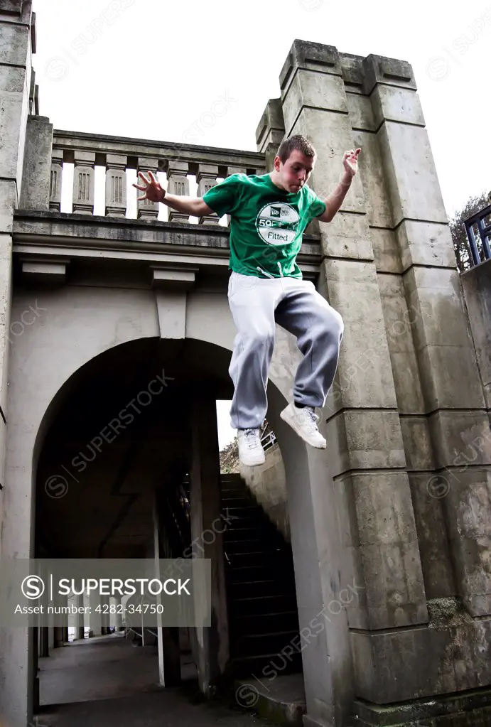 Wales, Conwy, Llandudno. A parkour athlete jumping from a structure.