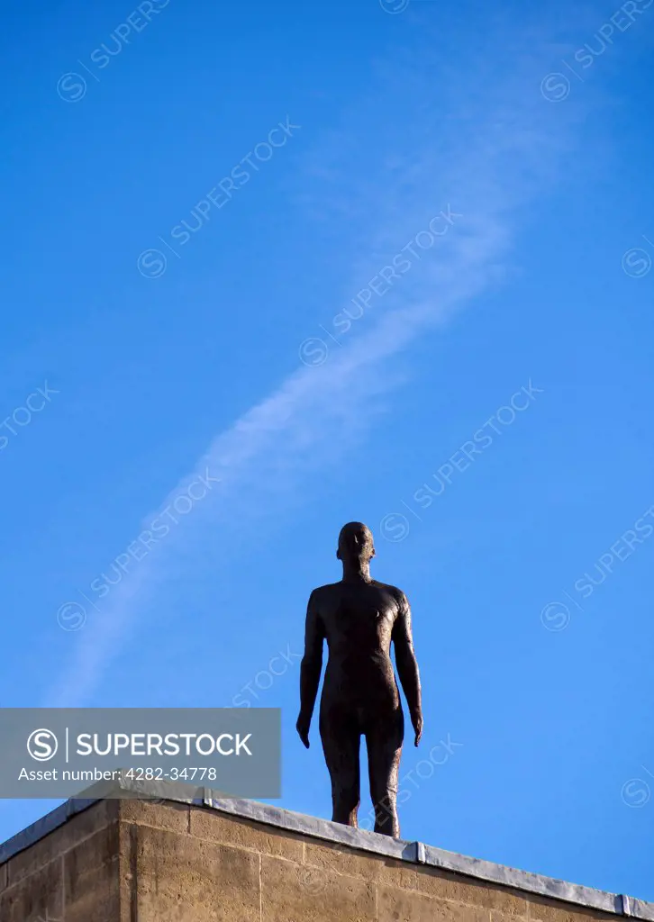England, Oxfordshire, Oxford. Antony Gormley's iron statue of a man on the roof of Blackwell's bookshop in Oxford.