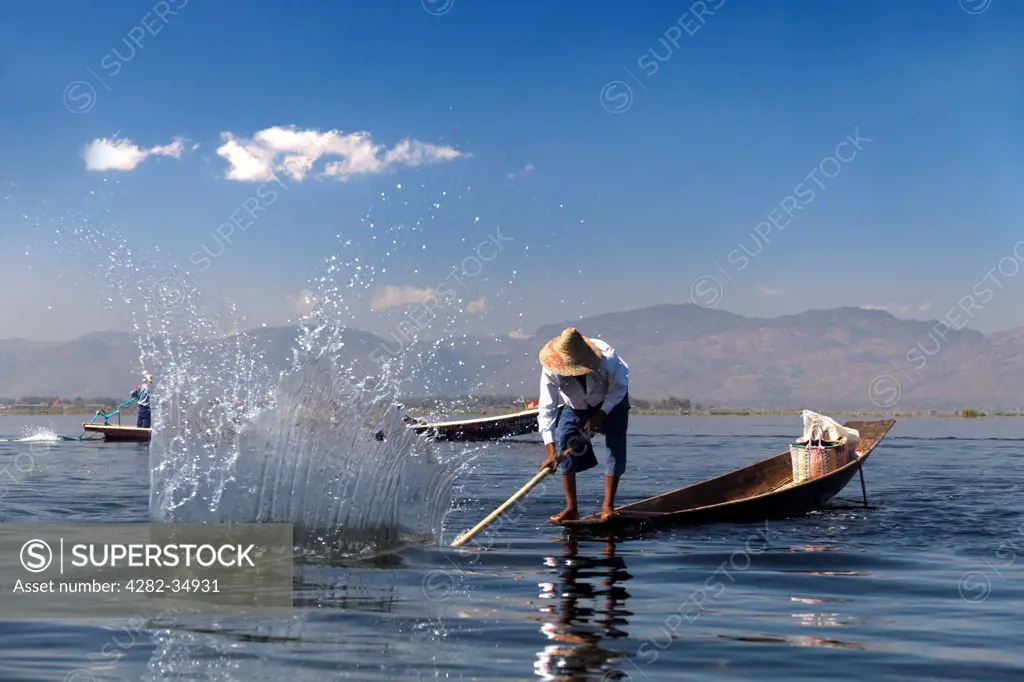 Myanmar, Shan, Lake Inle. Fisherman beating the water to attract fish on Lake Inle in Myanmar.