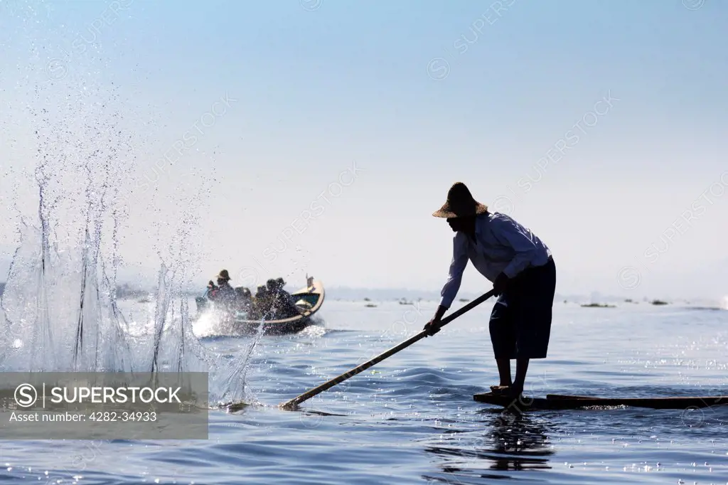 Myanmar, Shan, Lake Inle. Fisherman beating the water to attract fish on Lake Inle in Myanmar.