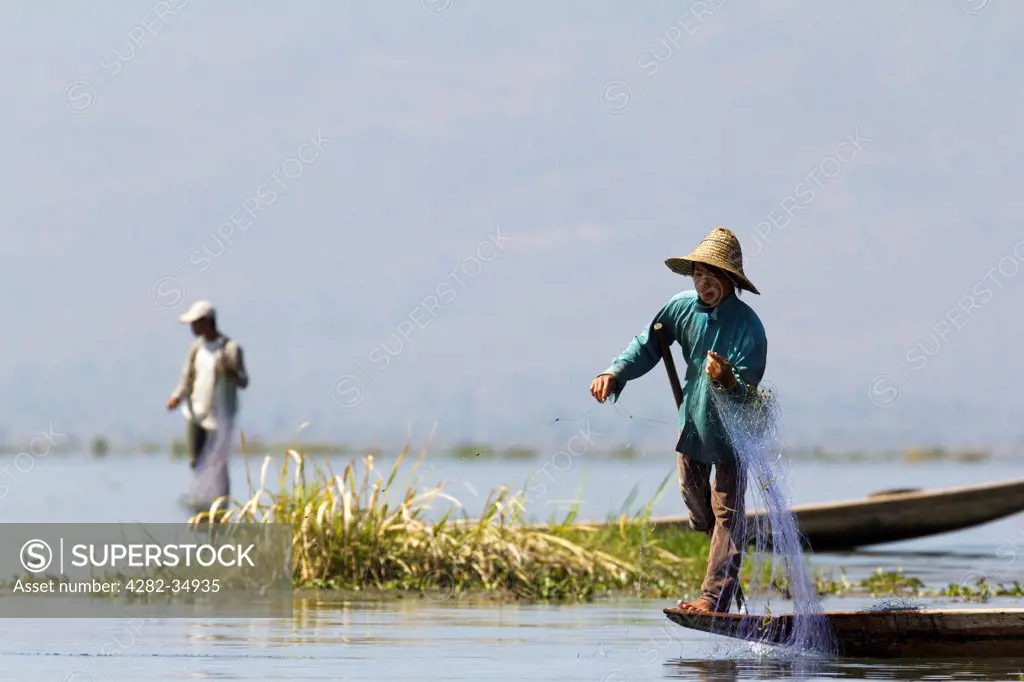 Myanmar, Shan, Lake Inle. Fisherman leg rowing and casting his nets on Lake Inle in Myanmar.