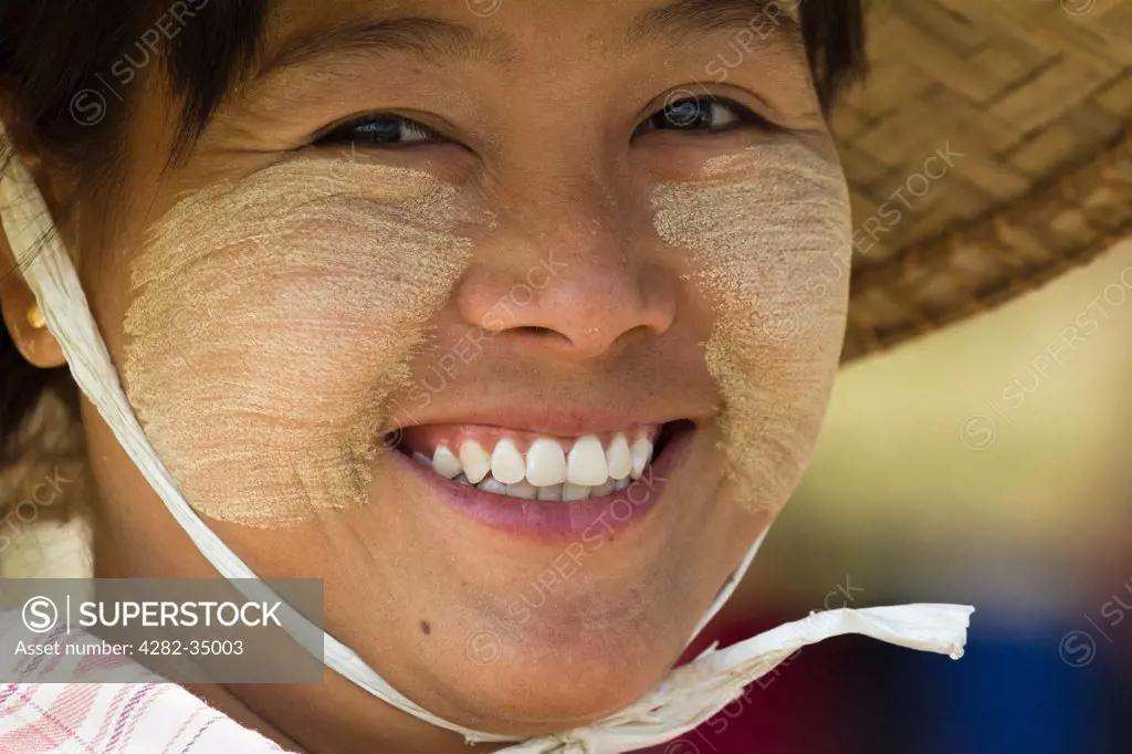 Myanmar, Mandalay, Mingun. A smiling girl with Thanaka makeup and wearing conical straw hat in Mingun in Myanmar.