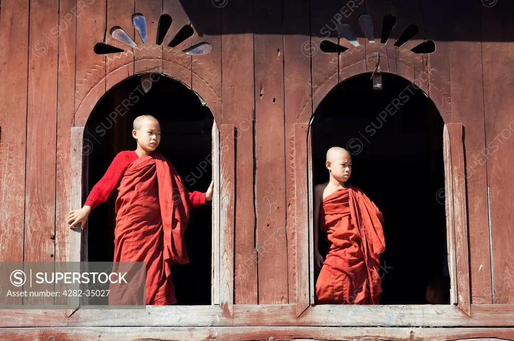 Myanmar, Shan, Lake Inle. Two young monks by the window in Shwe Yaunghwe Kyaung Monastery near to Lake Inle in Myanmar.