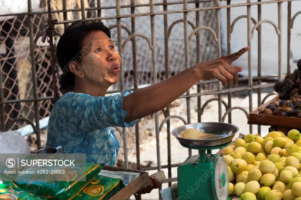 Myanmar, Yangon, Yangon. Old woman in fruit stall pointing in Bogyoke (formerly Scott) Market in Yangon in Myanmar.