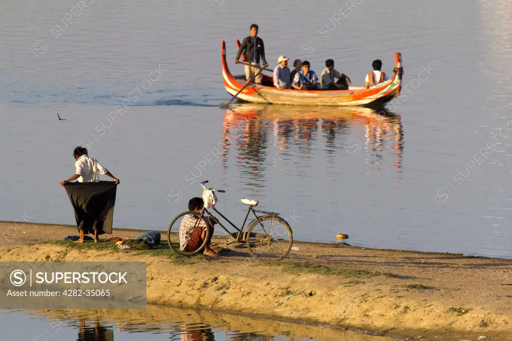 Myanmar, Mandalay, Lake Taungthaman. A tourist boat and passers-by on Taungthaman Lake in Myanmar.
