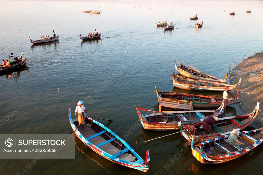 Myanmar, Mandalay, Lake Taungthaman. Tourist pleasure boats plying their trade by U Bein Teak Bridge across Taungthaman Lake in Myanmar.