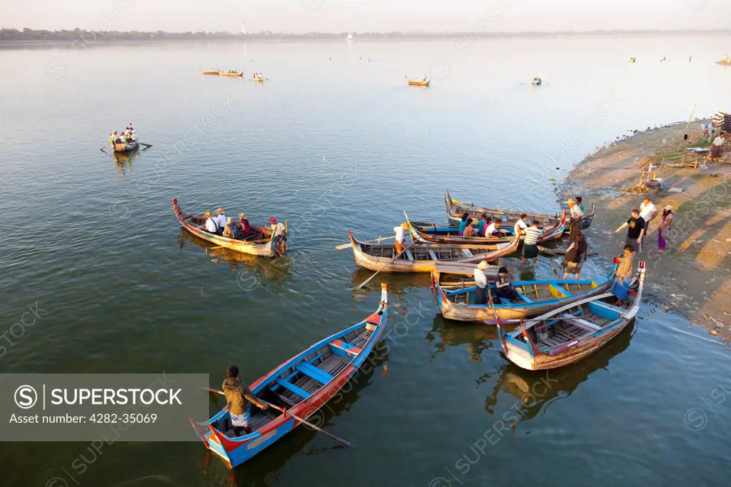 Myanmar, Mandalay, Lake Taungthaman. Tourist pleasure boats plying their trade by U Bein Teak Bridge across Taungthaman Lake in Myanmar.