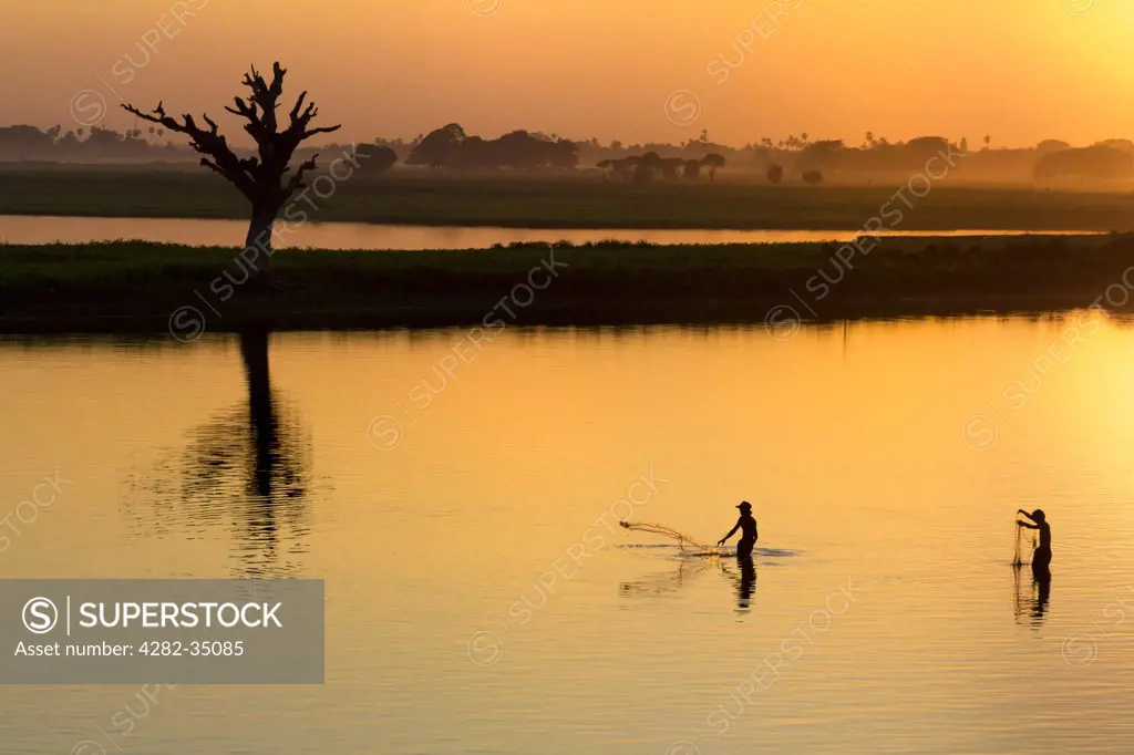 Myanmar, Mandalay, Lake Taungthaman. Fishermen on Taungthaman Lake in Myanmar at sunset viewed from U Bein Teak Bridge.