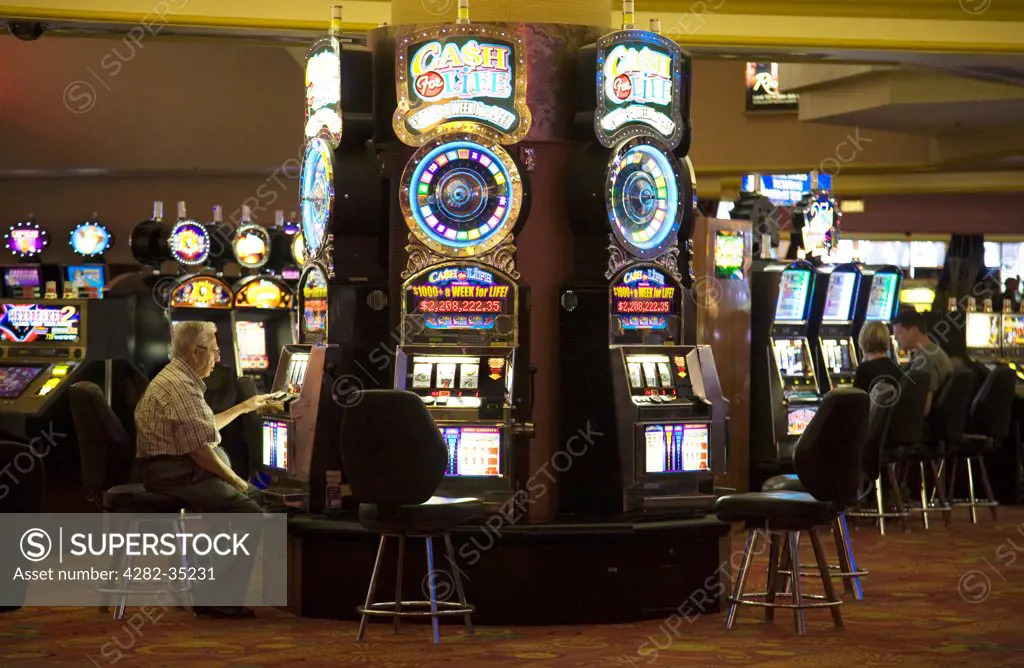 USA, Nevada, Las Vegas. A man plays the slot machines at the Stratosphere hotel and casino in Las Vegas.