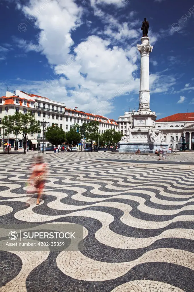 Portugal, District of Lisboa, Lisbon. Woman in red dress walking across Praca dom Pedro IV or Rossio Square.