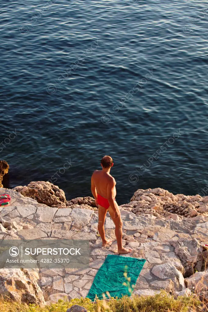 Croatia, Istria, Rovinj. A sunbather looking out to sea on the Istrian coast.