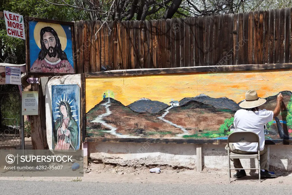 USA, New Mexico, Chimayo. An artist completes his mural.