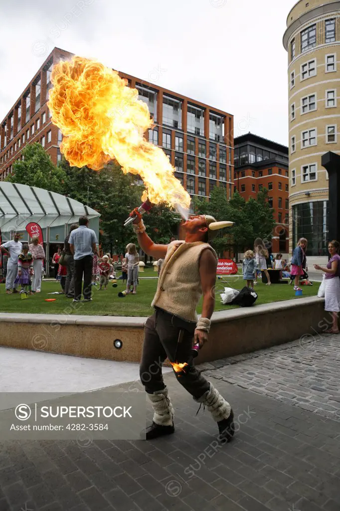 England, West Midlands, Birmingham. Fire eater at Brindleyplace. This area is named after the 18th century canal engineer, James Brindley, around which the buildings are grouped.