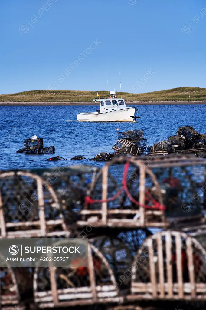 USA, Massachusetts, Cape Cod. Wooden lobster traps and a boat in Nauset Harbor.