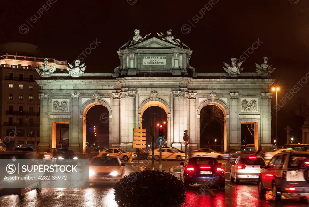 Spain, Iberian Peninsula, Madrid. Traffic drives past the La Puerta De Alcala monument at night.