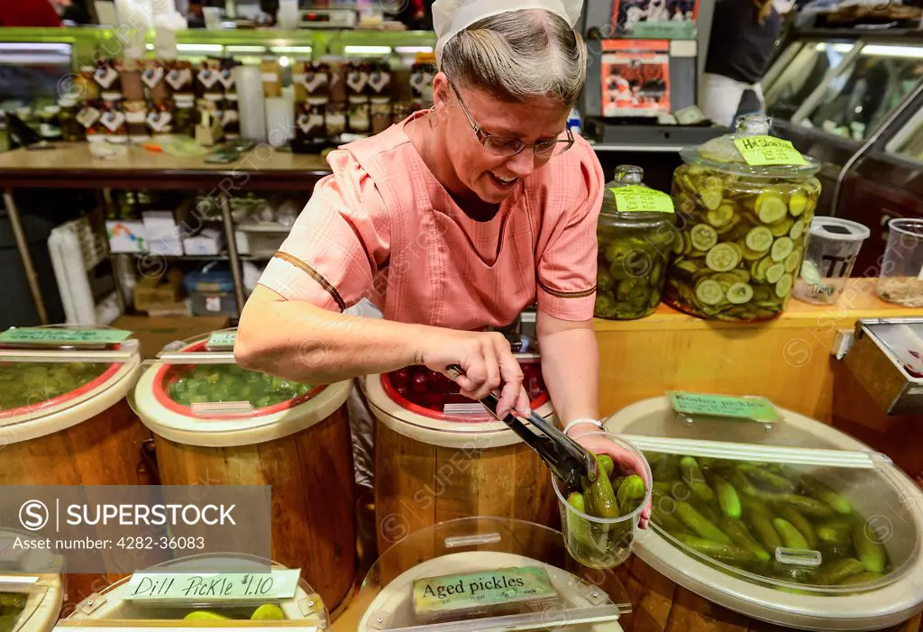 USA, Pennsylvania, Philadelphia. A woman serves pickles at Reading Terminal Market.
