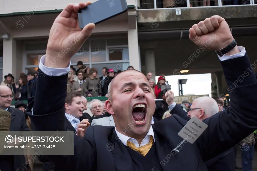 England, Gloucester, Cheltenham. A man is shouting with joy as the Gold Cup Day winner crosses the finishing line.