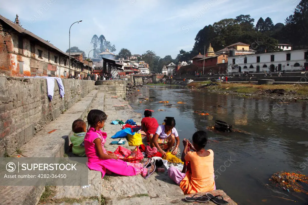 Nepal, Kathmandu, Pashpatinath. Girls washing clothes in the Bagmati River.